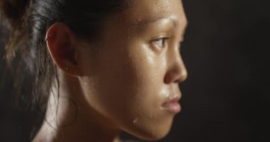 Kadın sporcu kameradan uzağa bakarak terliyor.