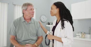 Siyahi kadın doktor yaşlı adama olumlu bakıyor.