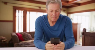 Beyaz bir erkek cep telefonuna bakıyor. Olgun yaşlı bir adam mesaj göndermek için akıllı telefon kullanıyor.