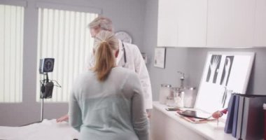 Orta yaşlı bir doktor, beyaz bir kadın hastayla tanışıyor.