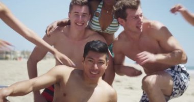 Sağlıklı genç grup çok etnik arkadaşıyla sahilde kameraya gülümseyen