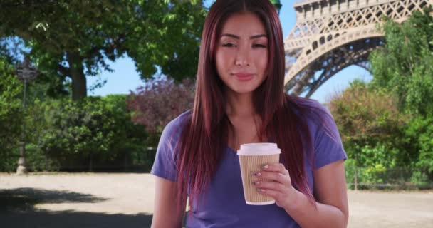 エッフェル塔の近くで可愛いアジア系女性がコーヒーカップを持っている姿 パリでコーヒーを楽しむ幸せな日本人女性 — ストック動画