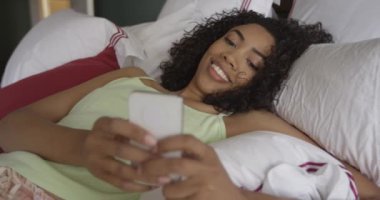 Yatakta mesajlaşan mutlu siyah kadın