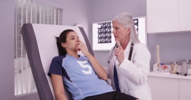 İyi görünümlü bayan sporcu kıdemli hekim tarafından spor yaraları inceleniyor.