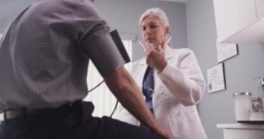 Hemşire erkek hastanın kan basıncını ölçüyor.