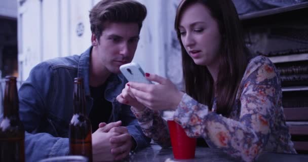 Cute Young Couple Sitting Bar Patio Using Cell Phone Smartphone — Stock Video