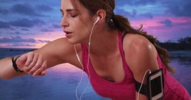 Genç milenyum kadını koşarken bileğindeki spor takip cihazını kontrol ediyor. 20 'li yaşlarda bir kadın koşudan sonra mola veriyor..