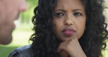 Genç hippi erkekler ve kadınlar dışarıda oturup konuşuyor ve birlikte gülüyorlar.