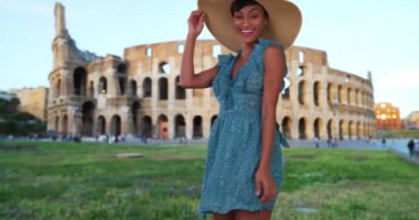 Roma, İtalya 'da tatil yapan genç ve çekici bir Afro-Amerikalı kadın Colosseum' un yakınındaki kameraya mutlu bir poz veriyor. Aktif genç modern kadın tatildeyken heyecanını ifade ediyor. 4k