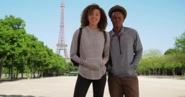 Eyfel Kulesi 'nin önündeki portre için mutlu, çekici siyah erkek ve kadın pozu. Milenyum çifti Paris 'te yaz günü kameraya gülümsüyor. 4k