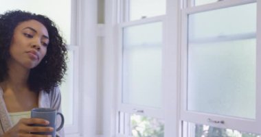 Siyah kadın evde bir fincan kahveyle dinleniyor.