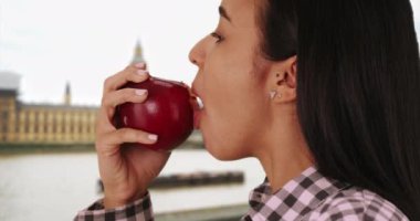 Latin Londra 'da lezzetli bir kırmızı elma yer. Genç İspanyol kız İngiltere 'nin başkentinde taze bir elma yiyor. 4k