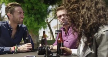 Bir grup arkadaş dışarıda içki içerek konuşuyor.