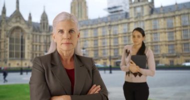 Westminster Sarayı yakınlarındaki ciddi bir politikacı kadın ve asistanının portresi. Londra caddesinde kendine güvenen iş ortakları. 4k