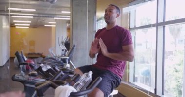 Sağlıklı formda bir çift. Siyah adam ve İspanyol kadın. Sabit bisiklete binip spor yapıyorlar.