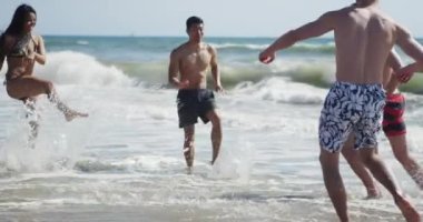 Irklar arası genç arkadaş grubu sahilde su sıçratıyor.