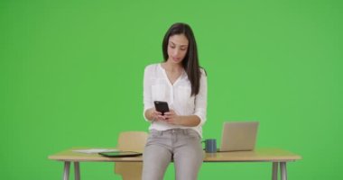 Latin bir iş kadını akıllı telefonunu yeşil ekranda kullanır. Anahtar ya da birleşik olmak üzere yeşil ekranda.
