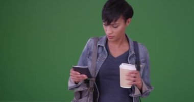 Siyah kadın yeşil ekranda elinde kahve tutarken büyük bir çantada pasaport arıyor. Anahtar ya da birleşik olmak üzere yeşil ekranda.