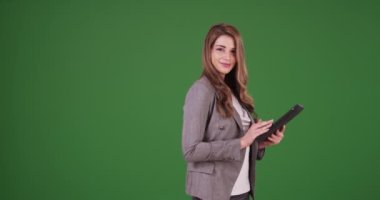 Mutlu ve güzel iş kadını tablet kullanıyor ve yeşil ekranda kameraya gülümsüyor. Anahtar ya da birleşik olmak üzere yeşil ekranda.