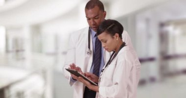İki siyahi tıp uzmanı, tablet kullanırken bir hastayı tartışıyor. Afro-Amerikalı doktorlar kendi evlerindeyken konuşurlar. 4k
