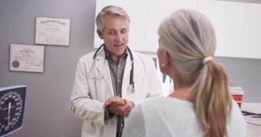 Kıdemli kadın doktor olgun kadın hastaya danışmanlık yapıyor.