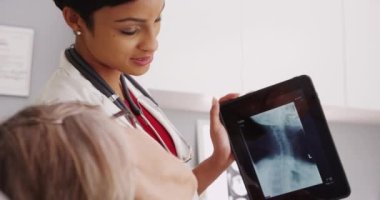X-ışını ile ilgilenen bir tablete bir doktorla olgun Bayan hasta