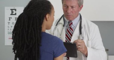 Siyahi kadın hasta, ofisinde doktoruyla konuşuyor.