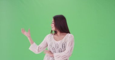 Asyalı kadın yeşil ekranda hayali bir nesneyi tutuyor. Anahtar ya da birleşik olmak üzere yeşil ekranda.