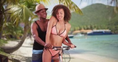 Afrika kökenli Amerikalı çift, sahil kruvazörlerini Karayipler 'de sürüyor. Siyah erkek ve kadın bikini ve şortlarıyla plajın yanında bisiklet sürüyorlar. 4k.