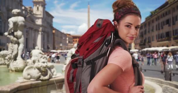 イタリアのローマを探検している若い女性は バックパックを背負ったままフォンタナ モロの近くにポーズをとっていた ナヴォーナ広場に立つローマを旅する冒険的な女性 — ストック動画