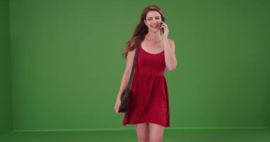 Kırmızı elbiseli genç bir kadın yeşil ekranda cep telefonuyla konuşuyor. Anahtar ya da birleşik olmak üzere yeşil ekranda.