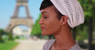 Çekici siyahi bir kadının Paris, Fransa 'da tatilinin tadını çıkardığı yakın çekim. Genç gülen Afrikalı turist Paris 'teki Eyfel Kulesi' nin yakınlarını geziyor. 4k