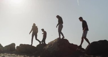 Dostlar sahildeki kayaların üzerinde yürüyorlar.