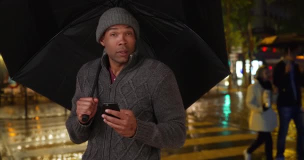 Afrikaanse Man Met Een Paraplu Buiten Een Regenachtige Avond Stad — Stockvideo
