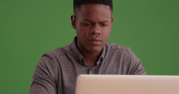 緑の画面のラップトップで働いている若い黒人男性 緑の画面でキーまたは構成されます — ストック動画
