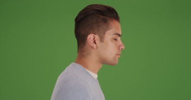 Yeşil ekranda alt kesimi olan genç milenyum adamının yan görüntüsü. Anahtar ya da birleşik olmak üzere yeşil ekranda.