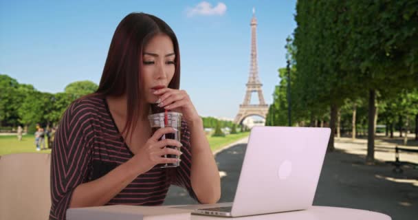 エッフェル塔の近くのラップトップでかなりアジアの女性のタイピング パリで勉強している女性はコーヒーを飲み コンピュータで仕事をする — ストック動画