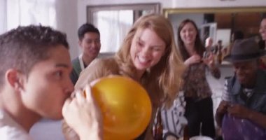 Arkadaşlar partide birbirlerini helyum balonlarıyla güldürüyorlar.