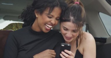 Mutlu kız arkadaşlar akıllı telefonla gülüyor ve gülüyorlar.