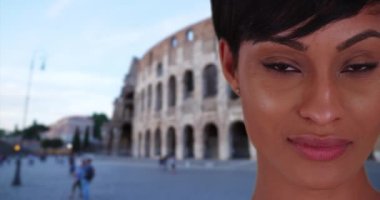 Çok güzel bir Afro-Amerikalı kadın Roma Kolezyumu 'nun önündeki kameraya tutkuyla bakıyor. İtalya 'da tatilde olan güzel etnik bayan izleyiciye dikkatle bakıyor. 4k
