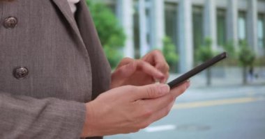 Genç iş kadını e-postaları incelemek için akıllı telefonu kullanıyor. Açık havada telefon kullanan esmer kadının yan görüntüsü. 20 'li yaşlarda akıllı telefon kullanan bir kadın