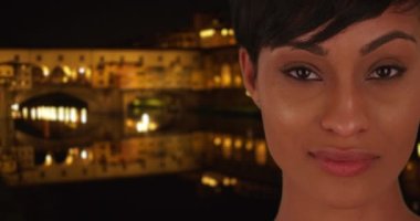 Güzel siyah dişi, Floransa 'da Ponte Vecchio yakınlarında dikilirken kameraya derin derin bakar. Muhteşem Afrikalı kadın geceleri İtalya 'daki izleyiciye özlemle bakıyor. 4k