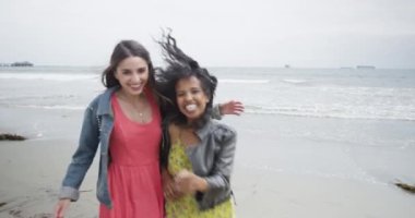 Kumsalda kameraya doğru koşan güzel kadınlar.