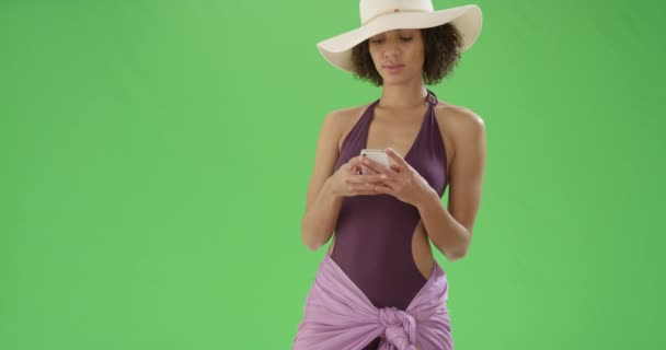 一位身穿泳衣的年轻的非洲裔美国妇女在绿色屏幕上的手机上 在绿色屏幕上键入或合成 — 图库视频影像