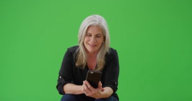 Güzel orta yaşlı kadın cep telefonu cihaz üzerinde metin okuma