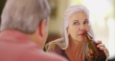 Orta yaşlı beyaz kadın erkek arkadaşıyla bira içiyor. Birkaç kıdemli arkadaş içkiyle sosyalleşiyor..