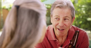 Yaşlı beyaz adam bir arkadaşıyla bira içiyor. Birkaç kıdemli arkadaş sosyal ve birlikte içiyorlar..