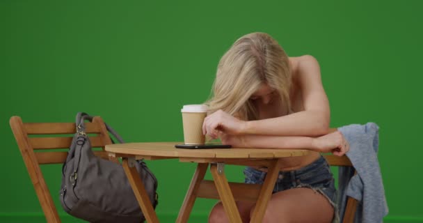 Młoda Dziewczyna Bikini Flirtuje Aparatem Siedząc Przy Stoliku Zielonym Ekranie — Wideo stockowe