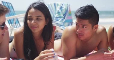Mutlu genç Interracial arkadaşlar beach konuşmayı yalan portresi kaydırma