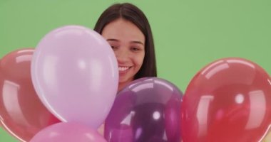 Yeşil ekranda bir sürü renkli balonu olan Millennial Latina. Anahtar ya da birleşik olmak üzere yeşil ekranda.